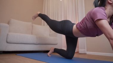 Asyalı genç bir kadın mavi minderde yoga yapıyor. Oturma odasında covid-19 sırasında egzersiz yapıyor. Egzersiz yapıyor, sakinleşiyor, sağlıklı, yoga ile esnek bir vücut. kişisel motivasyon 
