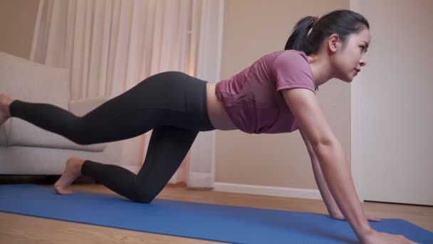 亚洲年轻女子在公寓客厅的蓝色垫子上练习瑜伽 在19岁以下儿童卧床期间锻炼 在家锻炼 平静放松 身体柔韧 还有瑜伽 自我激励 — 图库视频影像