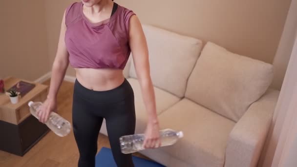Подходящая Женщина Выполняющая Домашнюю Работу Гостиной Кондо Стоя Упражнения Бутылкой — стоковое видео