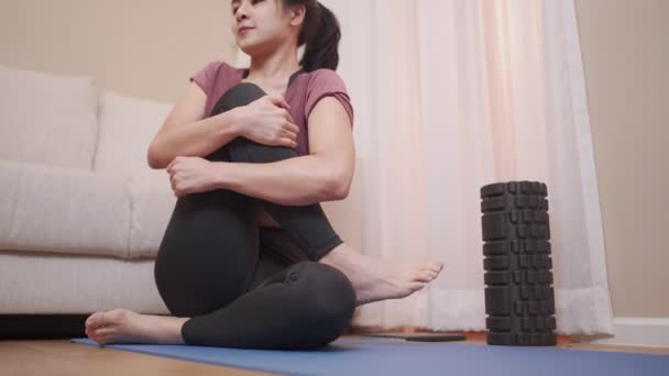 年轻的亚洲女人在家里客厅的瑜伽垫上做腿伸展运动 锁住鱼子酱 在家里客厅里做瑜伽练习 安静下来 放松生活方式 灵活的身体血液循环 — 图库视频影像