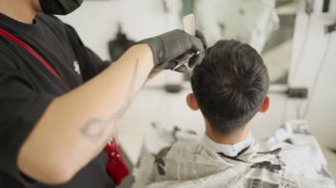 Asyalı adam saçlarını kestirdi. Karantina süresince, elektrikli saç kesme jileti Corona virüsü Covid-19 'daki adam berber iş dünyası salgınını yeniden başlattı.