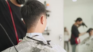 Temiz beyaz temalı Asyalı berber dükkanı, adam saçını kestiriyor. Corona virüsü Covid-19 sırasında berber işletmeciliğinin sahibi, saç kesme makası yeniden açıldı Salgından sonra küçük işletmeler açıldı