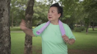 Asyalı son sınıf öğrencisi parkta koşuyor, egzersiz yapıyor, ağacın yanında duruyor, insan sağlığı, kadın sağlığı, hayat sigortası planı, rutin çalışma, daha iyi bir yaşam için sağlıklı yaşam.
