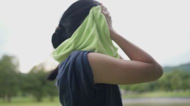 Parkta egzersiz yaptıktan sonra havluyla silen Asyalı kadın.