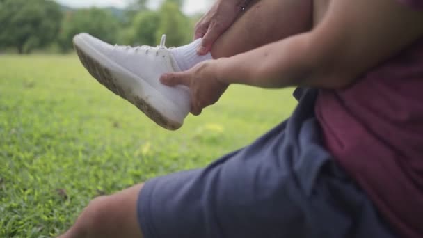 Pria Asia Memutar Pergelangan Kakinya Selama Latihan Dalam Taman Duduk — Stok Video
