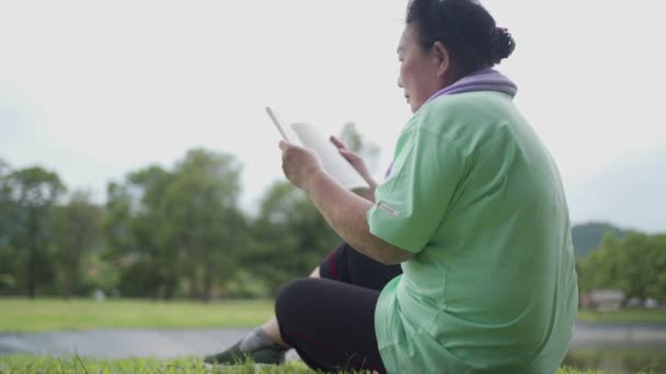 Wanita Senior Asia Duduk Beristirahat Dan Membaca Buku Taman Luar — Stok Video