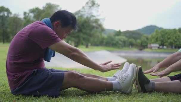 Азіатська Старша Пара Розтягує Ноги Рукою Ноги Сидячи Траві Під — стокове відео