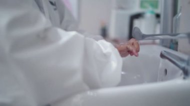 Elbiseli tıbbi personel dezenfekte edilmiş sabun kullanarak lavaboda ellerini yıkıyor, bakteri virüsünü önlüyor, Corona covid-19, ölümcül mikroplar, yeni normal sağlık hizmetleri, manken uzun kollu beyaz elbiseler giyiyor. 