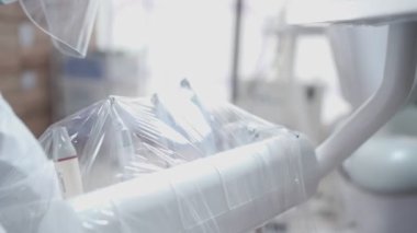 Diş kliniği aletlerinin hijyenik hazırlık süreci. Beyaz PPE giysisi giyen, diş operasyonu ekipmanlarını paketleyen, profesyonel dişçilikten önce hazırlayan personel, steril maddeler