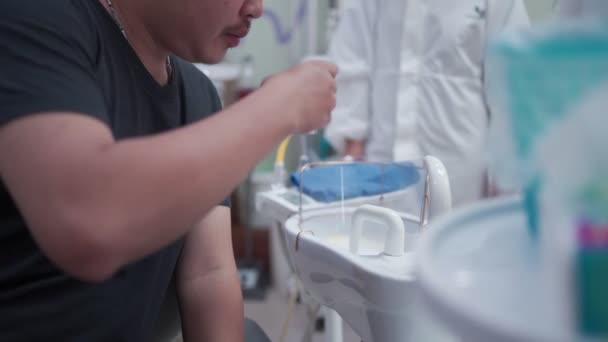 アジアの男性患者は 口腔歯科クリニックルームを洗い流し 座って 医療口頭検査 ピープスーツ 歯科手順 コロナウイルス中に 診断コンサルティングチェック バクテリアを殺す — ストック動画