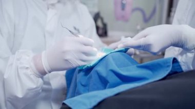Diş hekimi beyaz koruyucu PPE giysisi ve hasta üzerinde çalışan eldivenler, diş cerrahisi, hemşire yardımı uzman ekip çalışması, covid19 Corona virüs koruması, yakın çekim, sosyal sağlık hizmetleri