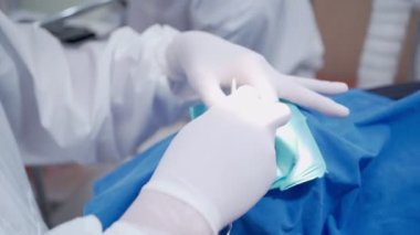 Beyaz eldivenli dişçiler, dişçi muayenehanesinde hasta bakımı almakla meşguller. Hemşirenin de yardımıyla. Diş dolgu prosedürü, yüksek hijyenik kalite kliniği, tükürük koruyucu kauçuk baraj.