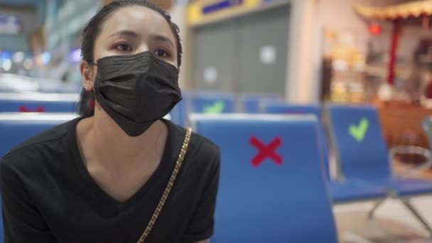 アジアの女性は黒いマスクを着用し 座って待ったアローン 社会的な距離の赤い印 2メートル離れた6フィート 新しい正常なCovid 19パンデミック 屋内ホールターミナル公共 社会問題を待っています — ストック動画