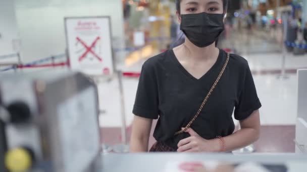 年轻的亚洲女性从机场候机楼的航空公司登记柜台获得机票 登机证 Covid 19流行病 新的正常旅行社交距离 航空公司航空业 — 图库视频影像