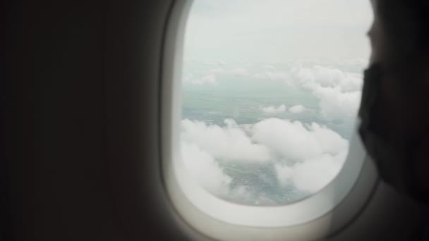 若いアジアの女性の乗客は飛行機の窓の座席に座って黒い表面のマスクを置きました 外の窓を見ます Covid 19新しい正常な旅行は社会的な距離を保ちます 安全な旅行の公共交通機関 — ストック動画