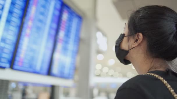 Asiatin Trägt Medizinische Maske Die Vor Dem Flugplanbildschirm Der Fluggesellschaften — Stockvideo