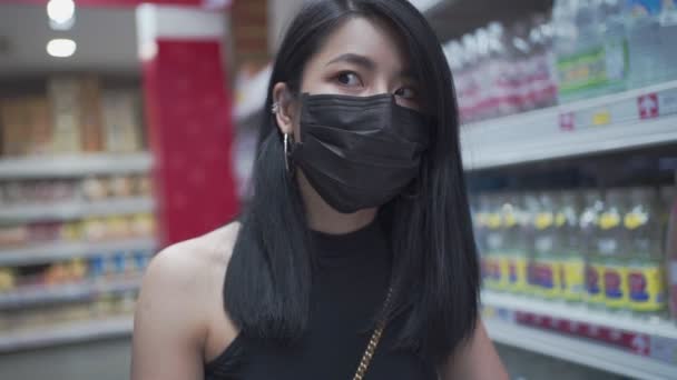 黒い顔のマスクの若い魅力的なアジアの女性は スーパーマーケット 食料品通路 女性がロックダウン中に供給を得る コビッド19の新しい正常なパンデミック 予算の生活費 社会問題 — ストック動画