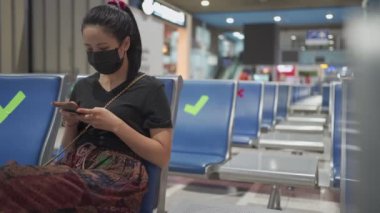 Asyalı kadın siyah yüz maskesi takıyor akıllı telefon, korona virüsü COVID-19 salgını, sosyal uzaklık levhası halk bankları, yeni normal yaşam alanı, 2 metre uzakta durun.