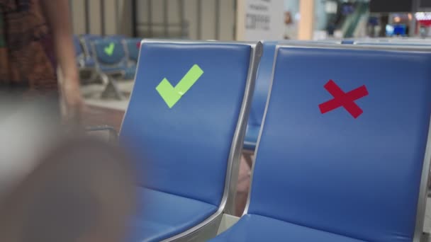 亚洲女人戴着黑色面具坐在椅子长椅上 社交距离概念检查标志 两米远 在Covid 19大流行期间是新常态 机场候机楼内 使用手机 — 图库视频影像