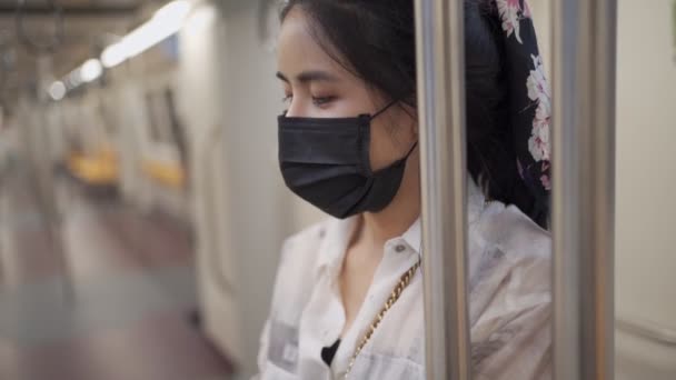アジアの若い女性は 地下鉄の列車の中に立って 黒い顔のマスクを着用し 新しい通常の社会的距離のライフスタイル 自己保護 空の地下鉄の車 感染性の遅い運動 公共交通機関のリスク — ストック動画