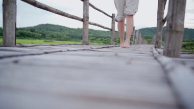 Kadın yavaşça çıplak ayakla kameraya doğru yürüyor. Tahta köprüde. Huzurlu, huzurlu bir sükunet.