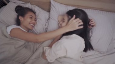 Asyalı iki lezbiyen çift battaniyenin içinde kucaklaşıyorlar, öpüşüyorlar, gülüyorlar, gülüyorlar, LGBTQ gurur duyuyorlar mutlu bir ilişki, homoseksüel toplum kavramı, kamera yukarıdan çekiliyor.