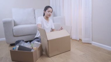 Geniş açılı bir kadın yeni bir daire alıyor, eşyaları ambalaj kutusundan çıkarıyor, işleri ayarlamak için koltuğa oturuyor, sahilde çalışıyor, konsept içinde taşınıyor, evde kalıyor.