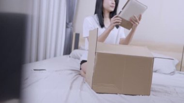 Asyalı genç bir kadın karton kutuyu açarak yatağın üzerine oturur, paketi, yeni daireyi, taşınma konseptini alır, evde kalır, yatak odasında eski güzel anıları olan eski defterleri açar.