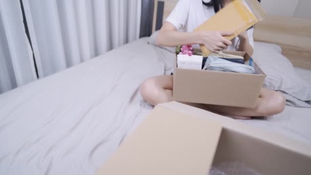 Asiática Joven Mujer Abierta Caja Entrega Paquetes Sentarse Dormitorio Interior — Vídeos de Stock