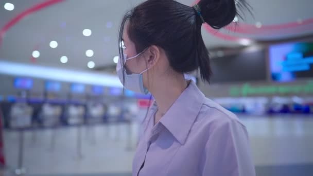 アジアの若い女性は 空港ターミナル廊下の中を歩くフェイスマスクを着用し 背景のカウンターでチェック ピックアップを待っています パンデミック危機 公共交通機関パンデミック — ストック動画