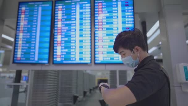 亚洲年轻男性乘客抬头看机场航班时间屏风 新的普通乘客 在空港机场候机室 戴口罩保护 头晕病毒 — 图库视频影像
