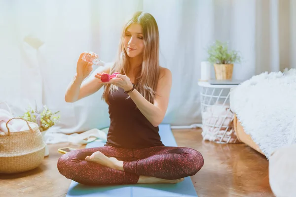 Jonge sportieve vrouw hand reiniger van een fles voor het desinfecteren van halter thuis. Ontsmettingsmiddel, desinfectie, reinheid en gezondheidszorg. Antibacterieel en Corona virus. Sport en recreatie. — Stockfoto