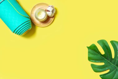 Pamuklu, yeşil yapraklı doğal ahşap mum ve sarılmış nane yogası, sarı arka planda pilates minderi. Metin için üst görünüm ve boşluk. Rahatla ve meditasyon konsepti.
