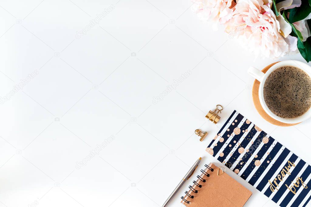 Top view of white working table background with cup of coffee putting on it. Flat lay glasses, peonies, golden paper binder clips, Notebook and pen. Desktop mock-up scene with copy space.