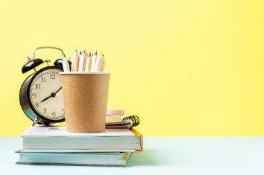 Siyah çalar saat, kitaplar ve kalemle okul pankartına geri dönüyoruz. Okul malzemeleri, nane arkaplanındaki diğer elementler kopya alanı olan boş arkaplan.