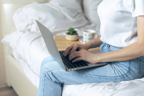 Crop Home office nő és távoktatás online oktatás. Boldog gyönyörű lány dolgozik laptop ülni az ágyon, és iszik kávét otthon. Számítógépes és online boltok használata. Egy kis szöveggel — Stock Fotó