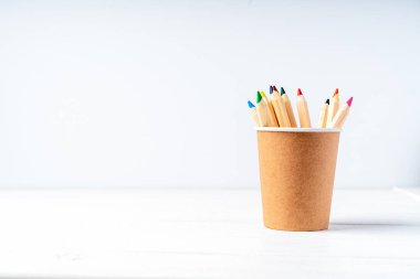 Kağıt bardaklar, kalemler ve geri dönüşümlü kağıtlar. Okul sıfır atığı, çevre dostu, doğal organik plastik konsepti. Dünya, kopyalama alanı ile ayrıştırılabilir.