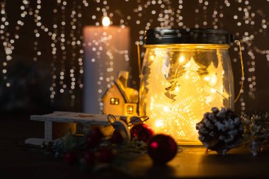 Cam kavanozda Noel ağacı, parlak ev, toplar, koni ve kartaneleri arkaplanlı simli mum. Kopya alanı olan Noel kartı dekorasyonu.