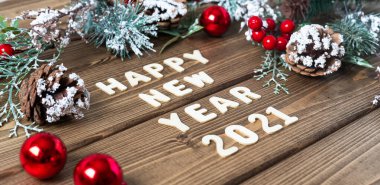 Mutlu yıllar 2021 kompozisyonu. Noel köknar dalları, eski koyu ahşap arka planda harflerle süslenir metin, düz yan görünüm.