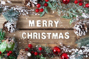 Mutlu Noel kompozisyonu. Kozalaklı dallar, böğürtlenler ve kar süslemeleri eski koyu ahşap arka planda. Üzerinde harfler yazılı, düz bir bakış açısı vardı..