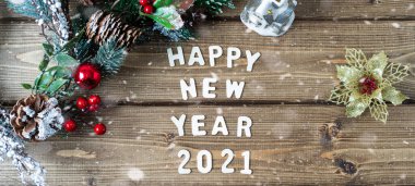 Mutlu yıllar 2021 kompozisyonu. Noel köknar dalları eski koyu ahşap arka planda harflerle süslenir metin, düz üst görünüm.