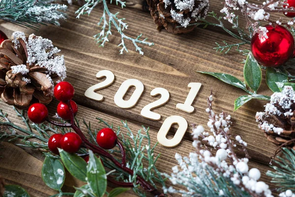New year 2020 change to 2021 concept. Christmas wreath with fir branches decorations on old dark wooden background with text, flat lay top view.