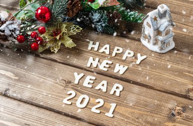 Mutlu yıllar 2021 kompozisyonu. Noel köknar dalları, eski koyu ahşap arka planda harflerle süslenir metin, düz yan görünüm.