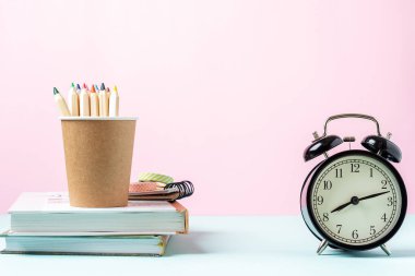 Çalar saat, kitaplar ve kalemle okul pankartına geri dönüyoruz. Okul gereçleri, pembe nane arkaplanındaki diğer elementler kopya alanı ile birlikte boş.