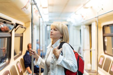 Sırt çantalı güzel yetişkin kadın portresi metroda duruyor ve önüne bakıyor..