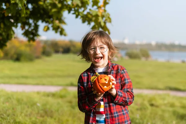 Niño lindo en gafas jugar con calabaza en el parque de otoño en Halloween. Los niños engañan o tratan. Diversión en otoño. Vestido niño —  Fotos de Stock