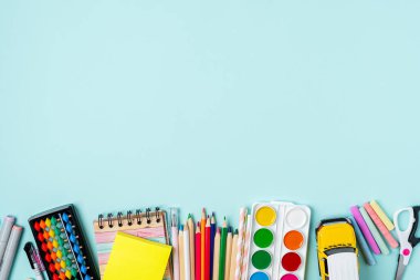 Modern, parlak, mavi ofis masaüstü, okul malzemeleriyle dolu bir masa. Boş alan etrafında mesaj için. Üst Görünüm Okul Konseptine Dönüş