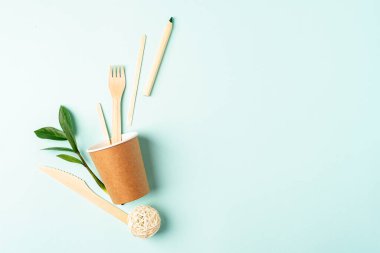 Kağıt bardak, yeşil yapraklar ve geri dönüşümlü çatal bıçak. Sıfır atık, çevre dostu, doğal organik plastik konsept. Masa takımı Dünya, kopyalama alanı ile biyolojik olarak çözünebilir.