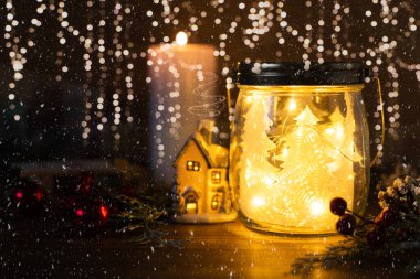Cam kavanozda Noel ağacı, parlak ev, toplar, koni ve kartaneleri arkaplanlı simli mum. Kopya alanı olan Noel kartı dekorasyonu.
