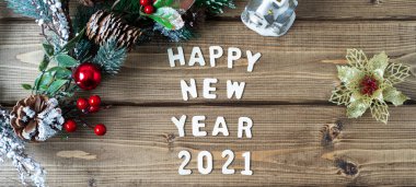 Mutlu yıllar 2021 kompozisyonu. Noel köknar dalları eski koyu ahşap arka planda harflerle süslenir metin, düz üst görünüm.